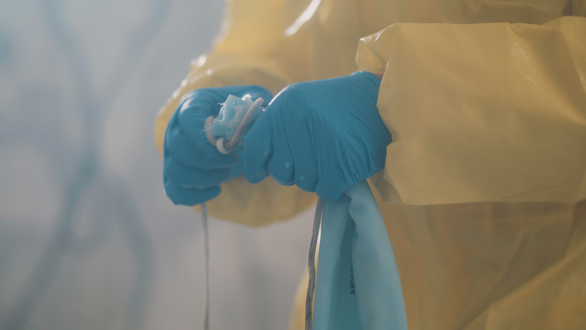 Detaljbilde Rørfornying - Rørfornyingsoperatør knyter epoxy-foring med blåhansker og gul vernedress